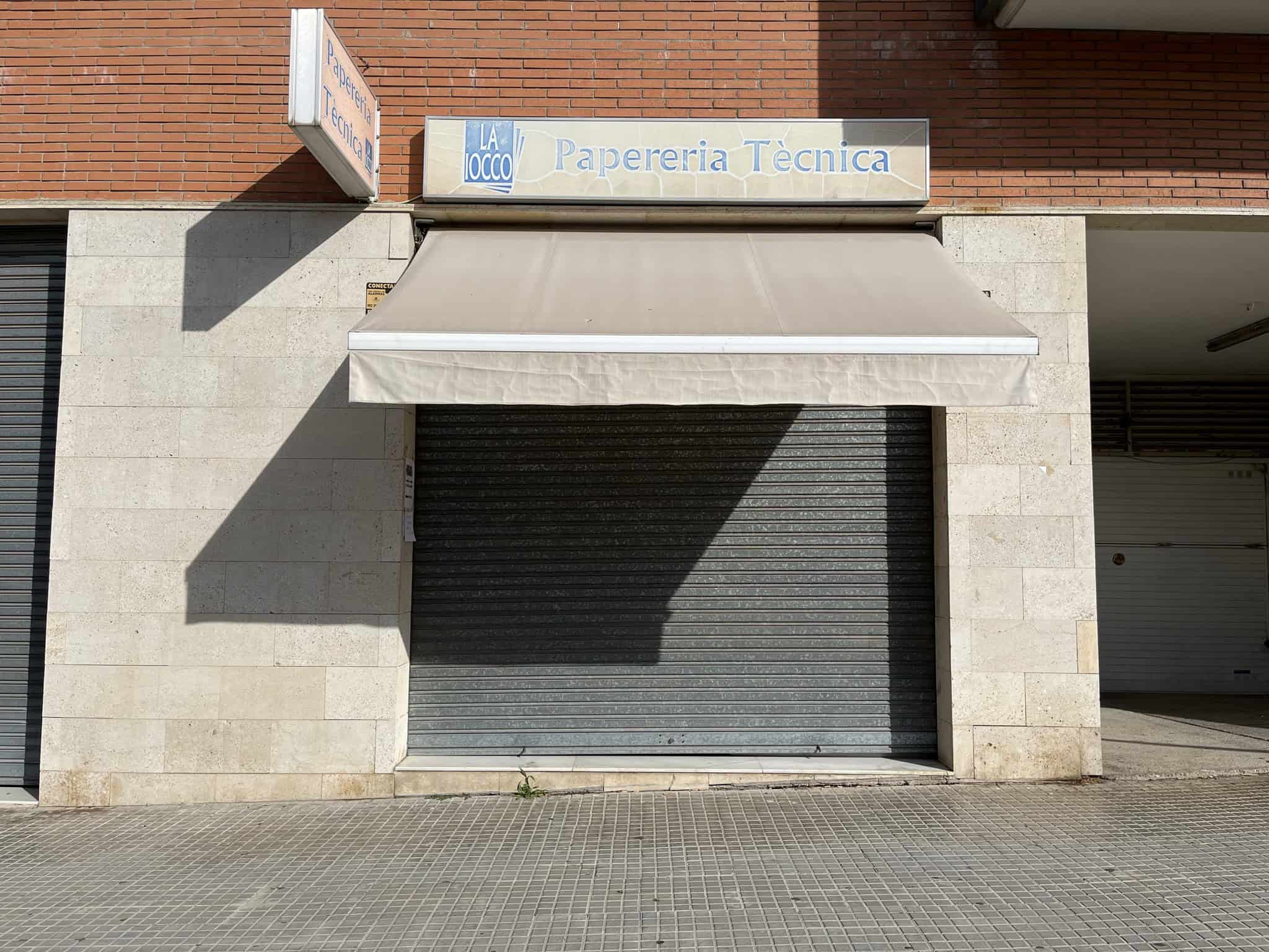 Façana del local amb persiana metàl·lica tancada i rètol de “Papereria Tècnica”.