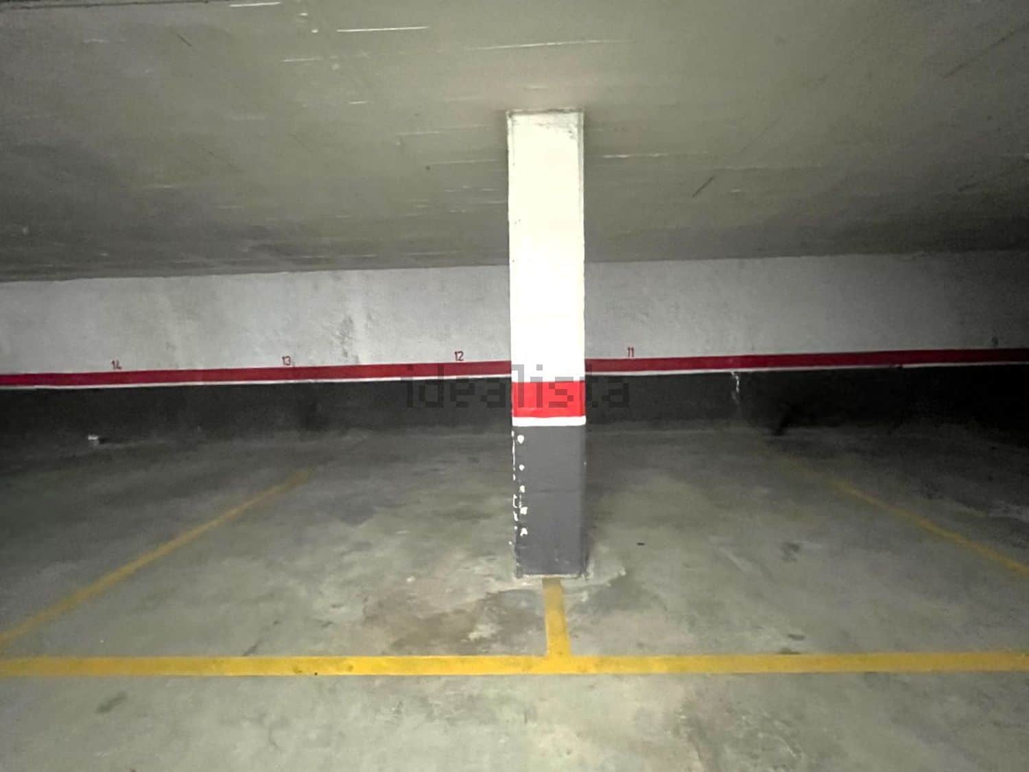 Reservat de pàrquing subterrani amb espai per a cotxes, senyalització i murs de formigó, ideal per a serveis immobiliaris i gestió d'immobles.