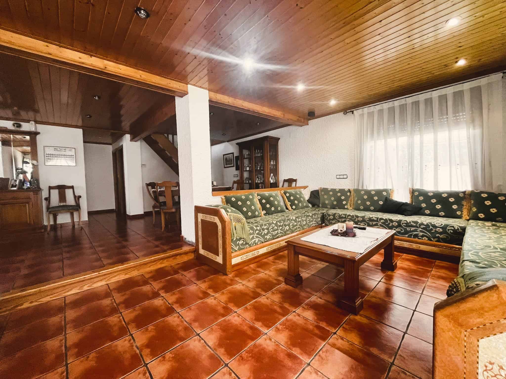 Amplia sala d'estar amb mobles de fusta, sofàs cap del carrer, parquet de terracota, il·luminació empotrada, i espai per a esdeveniments en una propietat immobiliària a Torra Advocats.