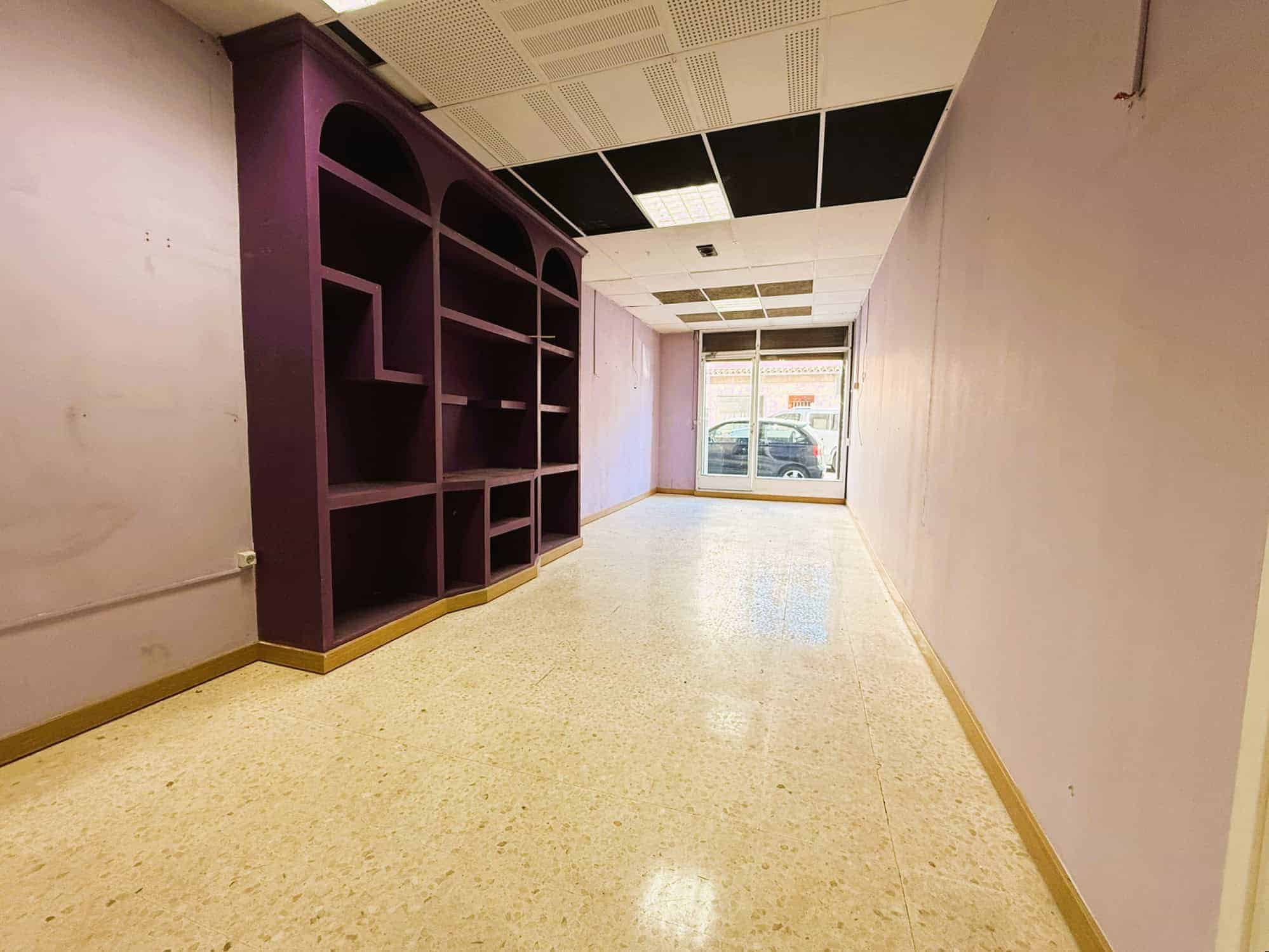 Mobles d'armariers a la immobiliària, espai de trobada per a professionals del sector immobiliari, oficina comercial buida amb gran finestra i sostre refatat, ideal per a oficina o negoci.