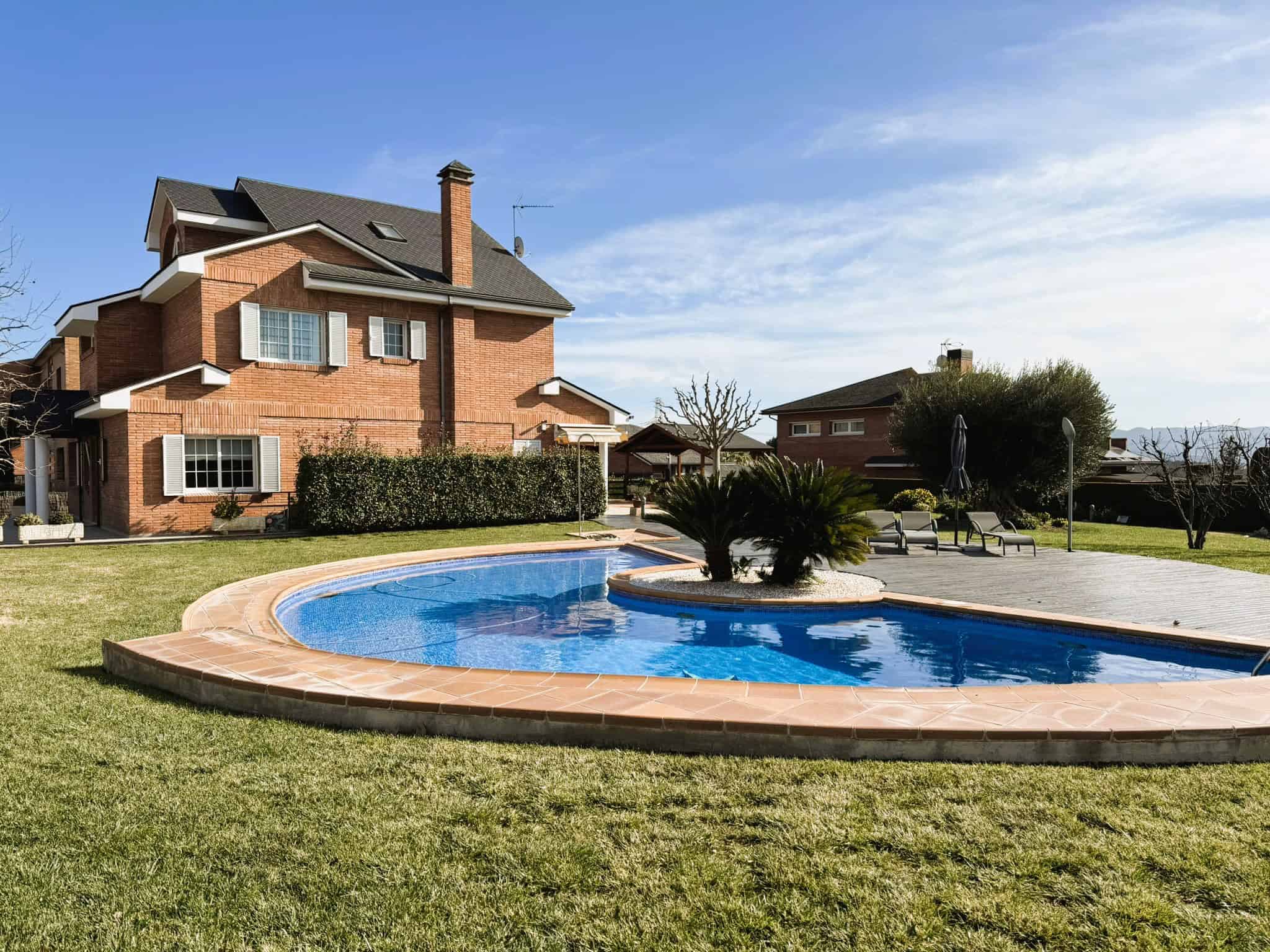 Piscina privada amb jardí i casa de pedra en zona residencial, serveis immobiliaris i assessoria legal immobiliària a Torra Advocats.