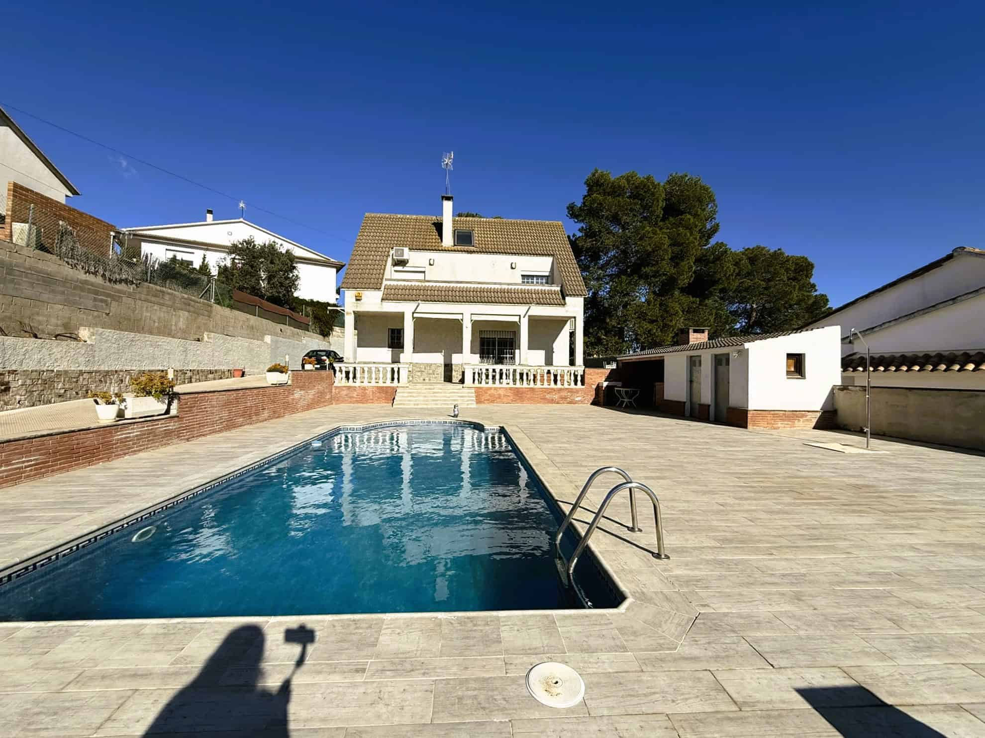 Piscina exterior de casa moderna amb ampli jardí i zona d'esbarjo, ideal per a habitatge amb serveis immobiliaris i financers a Torra Advocats.