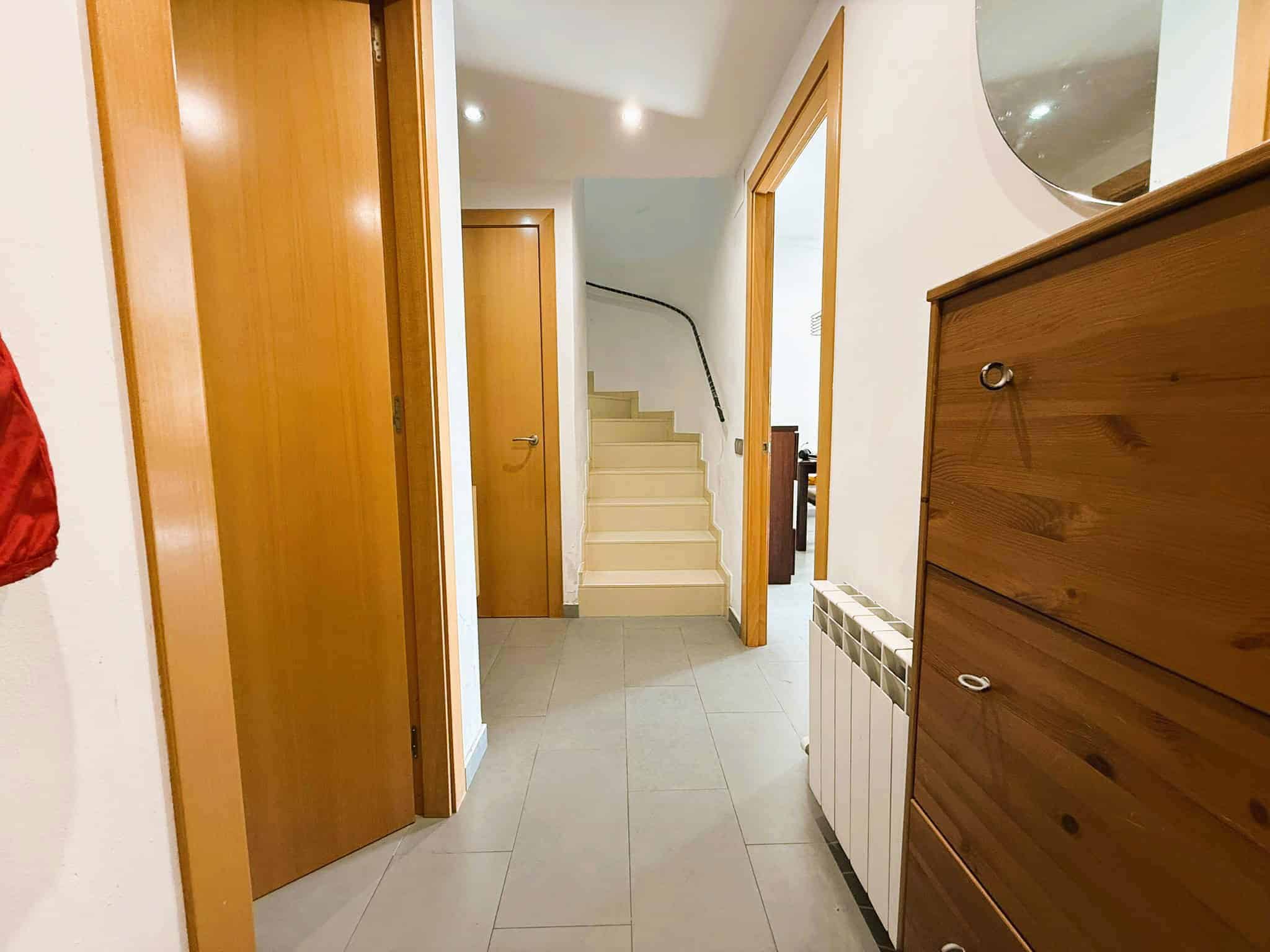 Esquerra, imatge d’un passadís interior d’un habitatge, amb portes de fusta i escales, ideal per a empreses immobiliàries i advocats especialitzats en immobles.