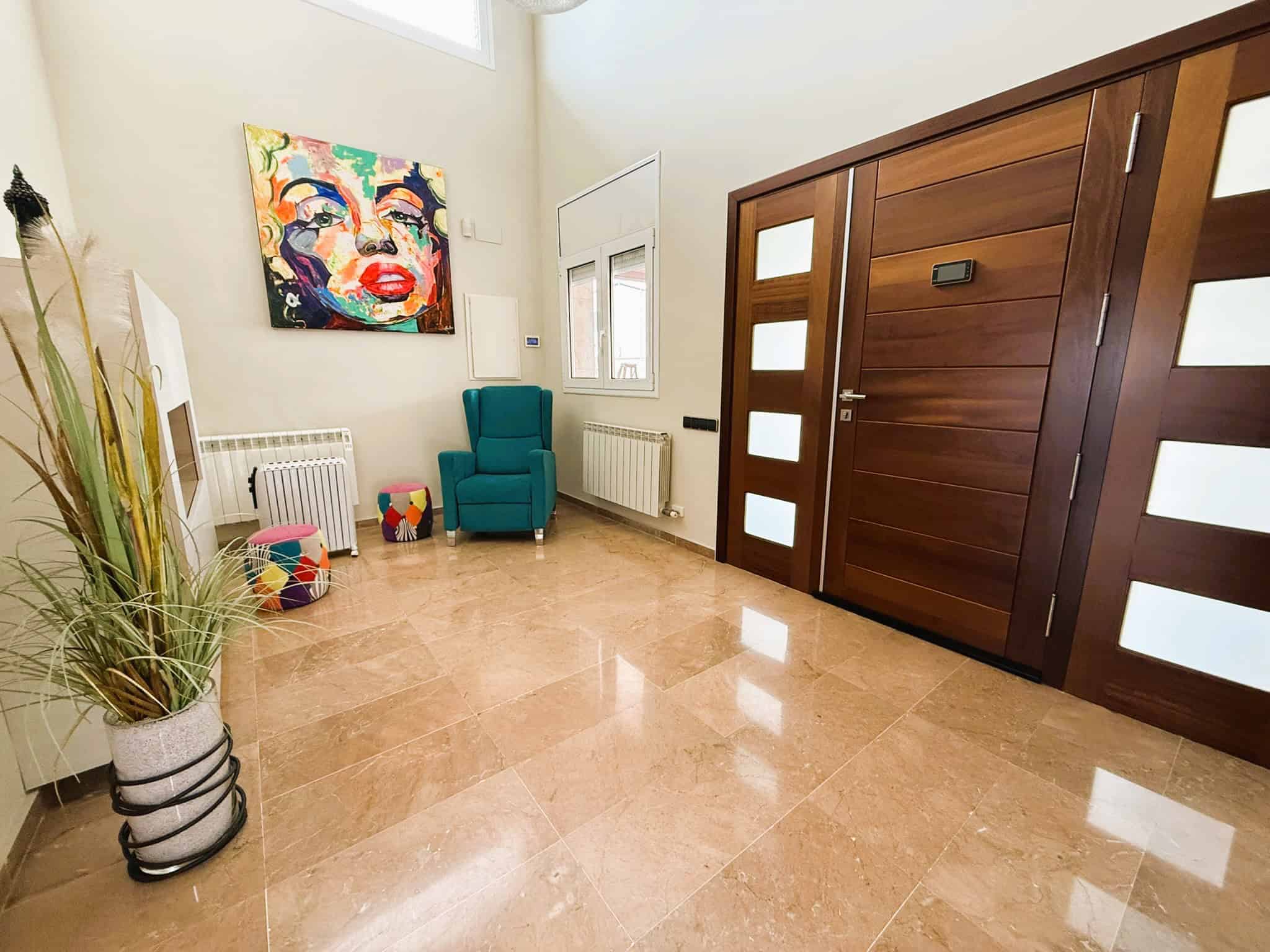 Puerta d'entrada de fusta modular amb detalls de vidre i sistema de seguretat, en un interior modern i acollidor d'habitatge amb decoració colorida i mobles còmodes.