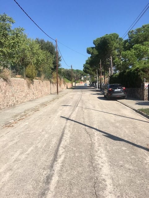 Ample carrer residencial amb arbres i cases familiars, ideal per a serveis immobiliaris i assessorament jurídic en immobles a la zona.
