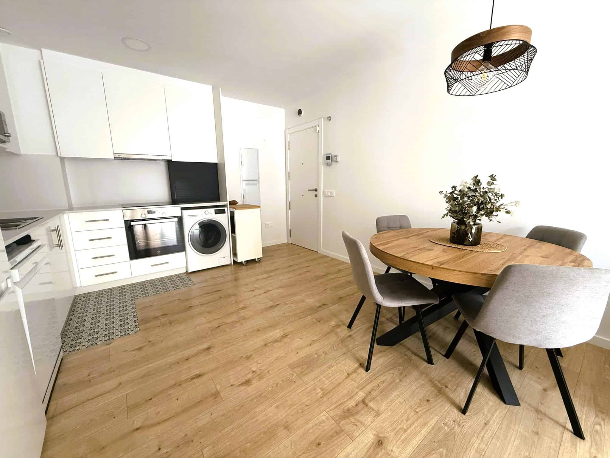 Llum modern, cuina oberta amb electrodomèstics, taula de menjador de fusta i cadires còmodes, decoració minimalista en habitatge amb sòl de parquet, il·luminació natural, arquitectura funcional, serveis immobiliaris, advocats especialitzats en inmobiliària, estratègia jurídica immobiliària.