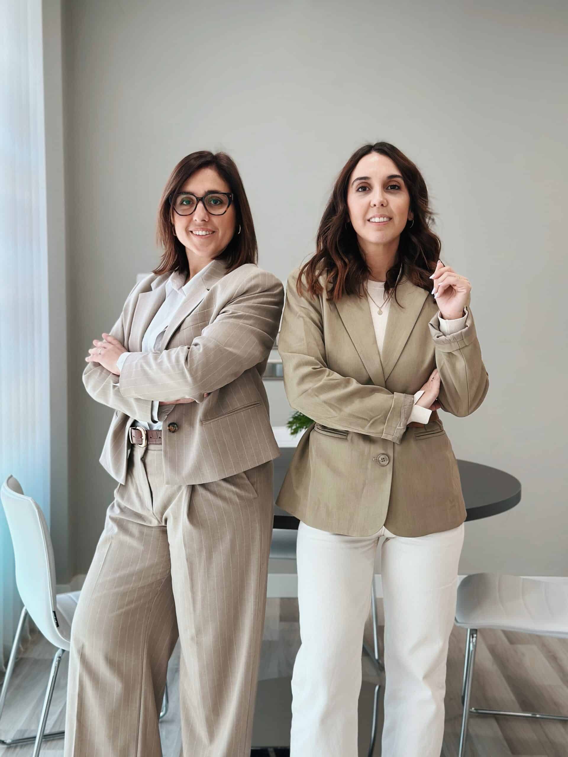 Estandard en advocacia immobiliària, dues dones professionals en vestimenta formal a la oficina.
