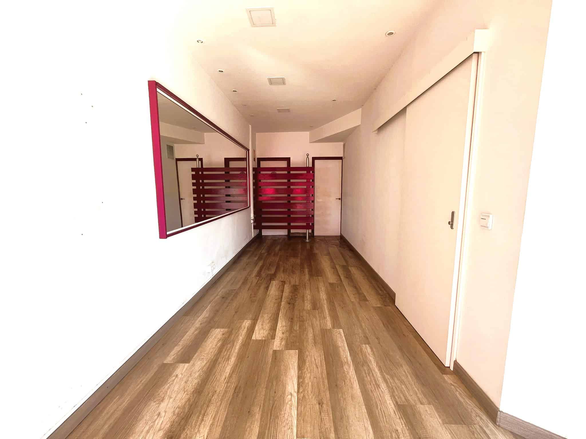 Amplia sala d'espera amb sòl de parquet, mirall i separadors de fusta en un entorn profesional d'advocats especialitzats en immobiliària.