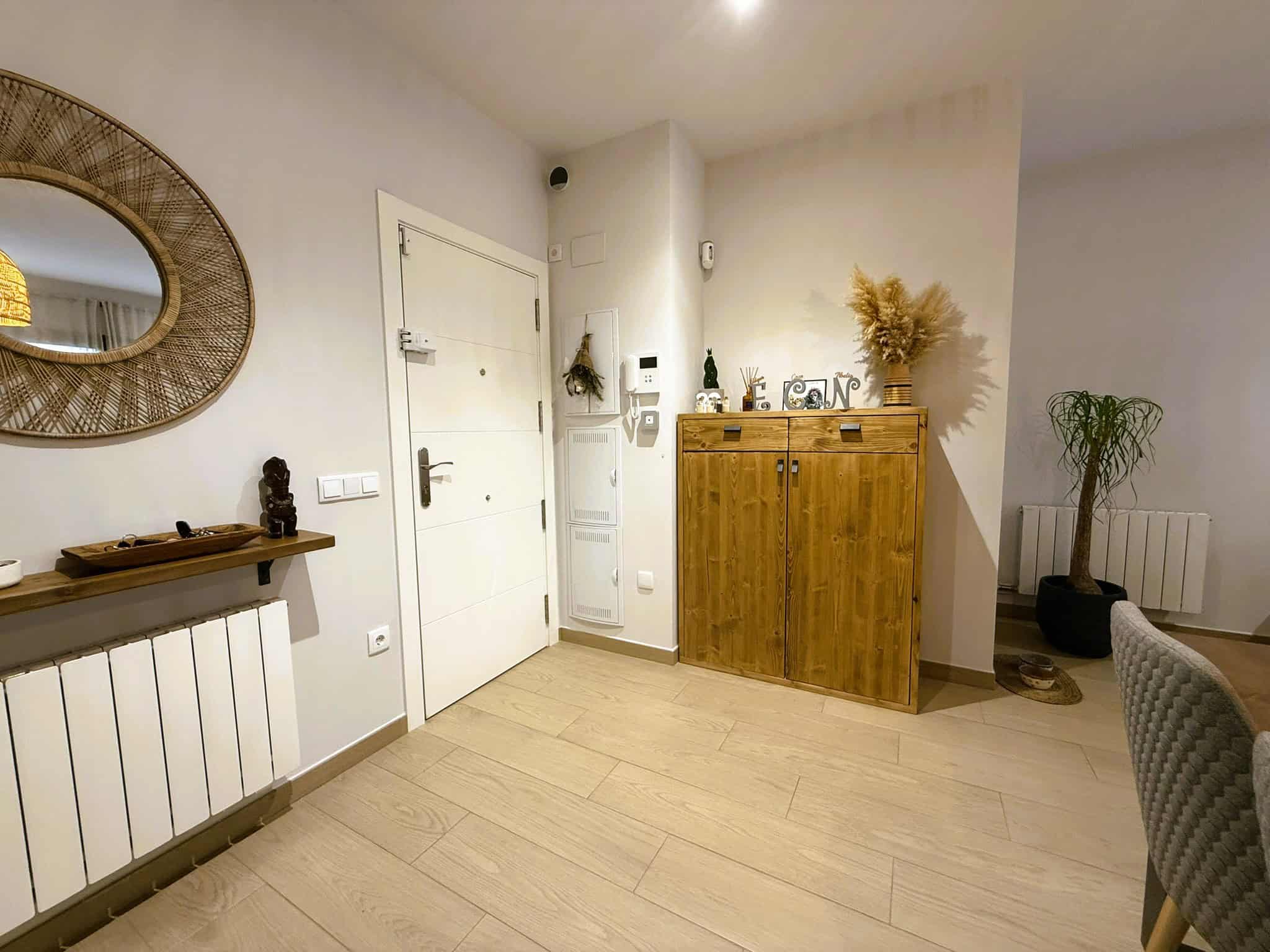 Procedimentals d'entrada a una vivenda, decoració moderna i acollidora amb mobles de fusta, mirall decoratiu i elements de design d'interior.