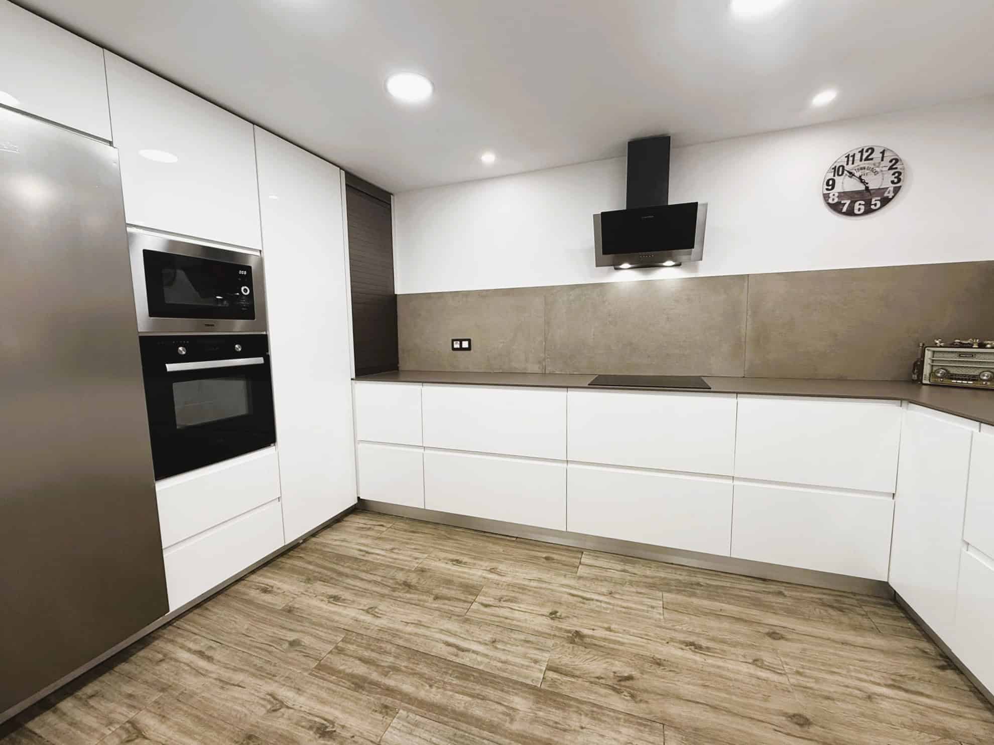 Cocina moderna amb mobles blancs, electrodomèstics de darrera generació i espai funcional, ideal per a gestió immobiliar i assessorament legal en transaccions immobiliàries.