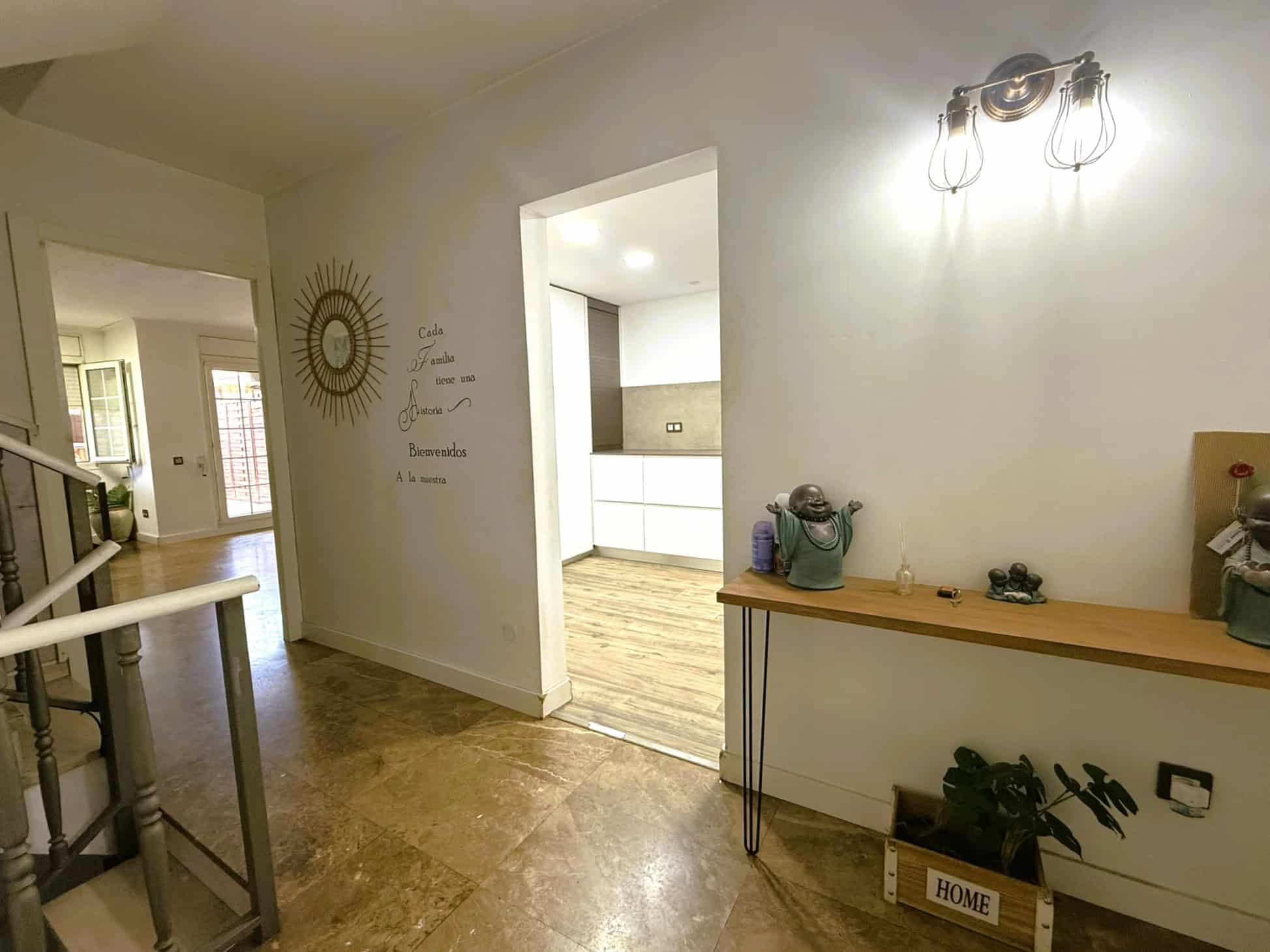 Esquerra: Portal interior d'una casa amb decoració moderna i lluminosa, sala d'entrada acollidora, amb motius de benvinguda i espai per a la família.