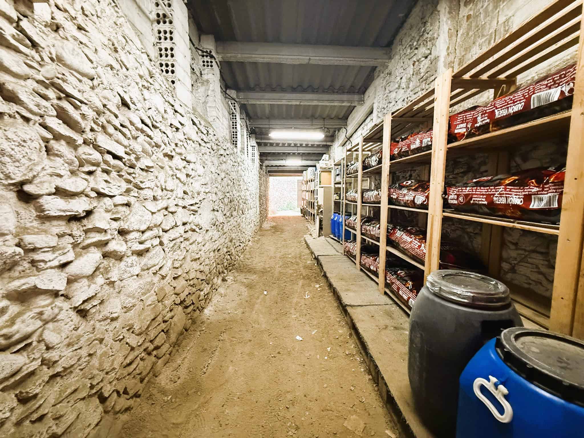 Documents, environment, and space of storage in rustic cellar or basement with stone walls, shelving with supplies, and tools for real estate or legal property management by Torra Advocats.