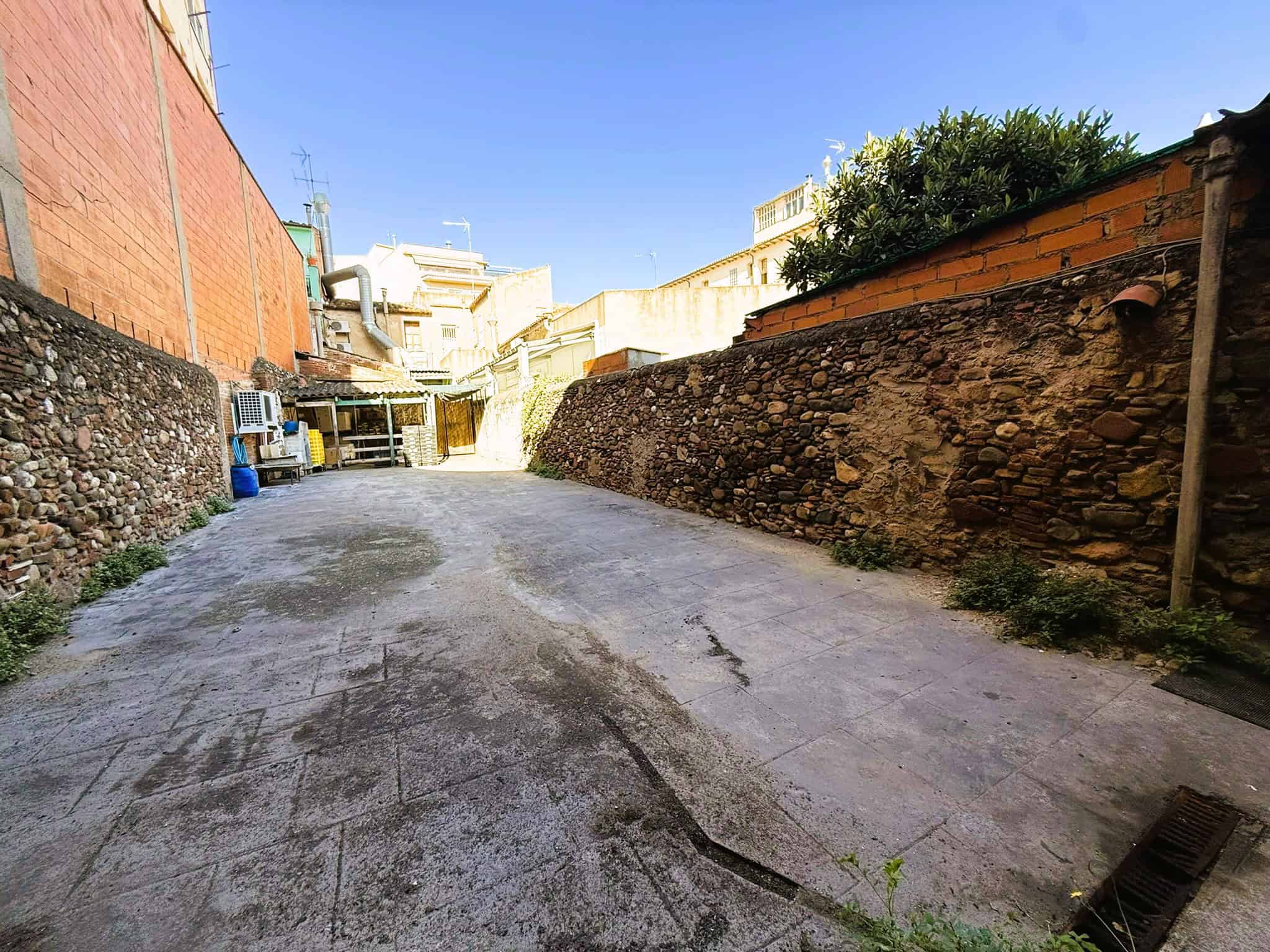 Pista d'aparcament interior a Barcelona amb parets de pedra i façana d'obra nova, ideal per a immobiliària, locals comercials o construcció de comunitats de veïns.