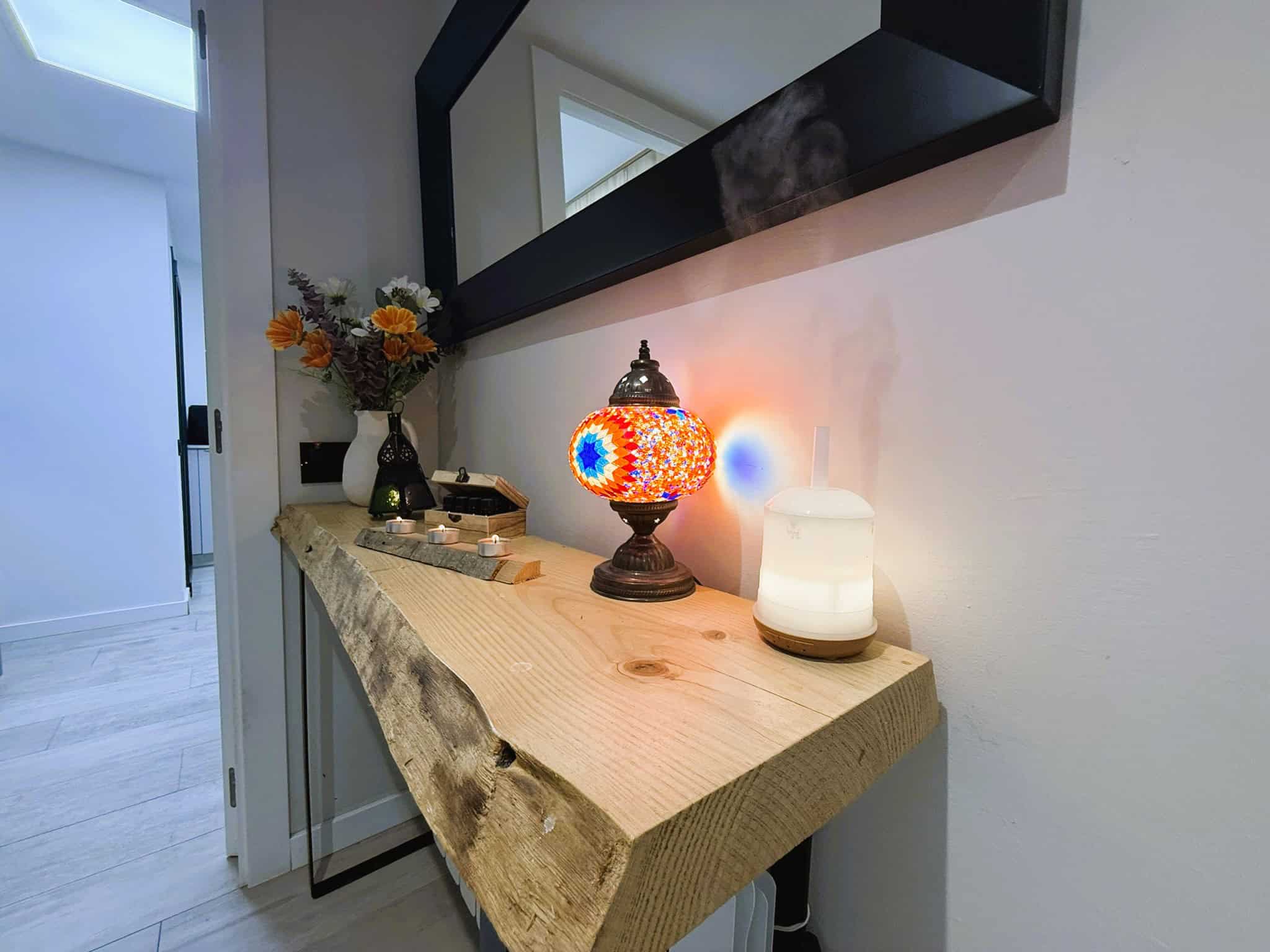 Colorit de taula de fusta natural amb decoració, làmpada de taula de mosaic de colors i difusor d'aroma, en un espai interior acollidor i modern.