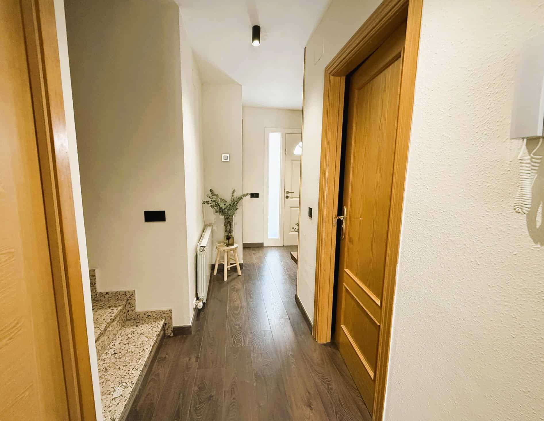 Imatge d'una entrada acollidora d'una casa adossada a Can Maiol, amb passadís modern i decoració senzilla.