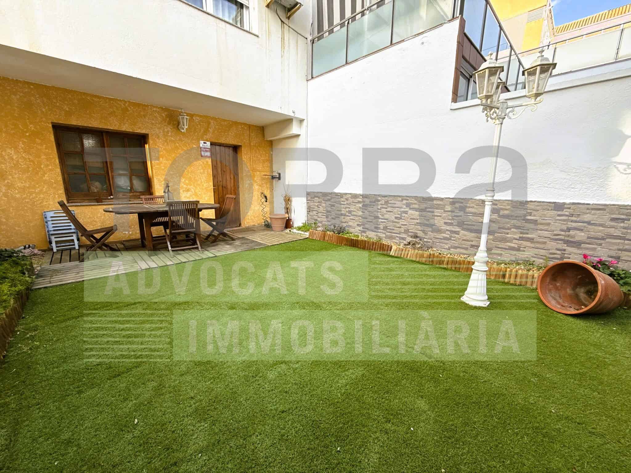 Pati interior amb jardí i mobiliari exterior, ideal per a espais d'oci i trobades, amb gespa artificial, il·luminació i decoració moderna.