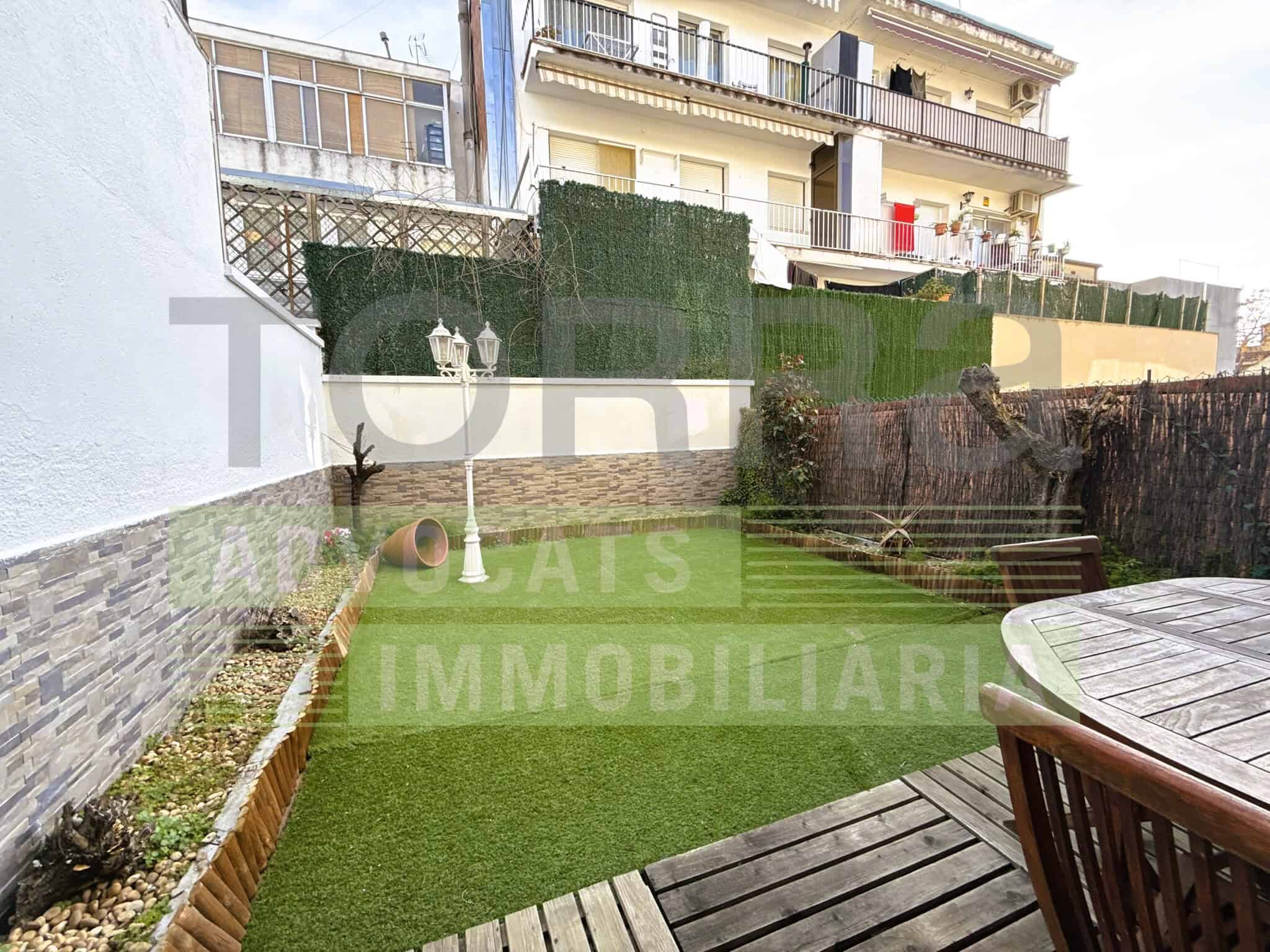 Escrit en alt: Jardí privat amb mobiliari i gespa artificial, ideal per a activitats a l'aire lliure i moments de relax a la propietat.