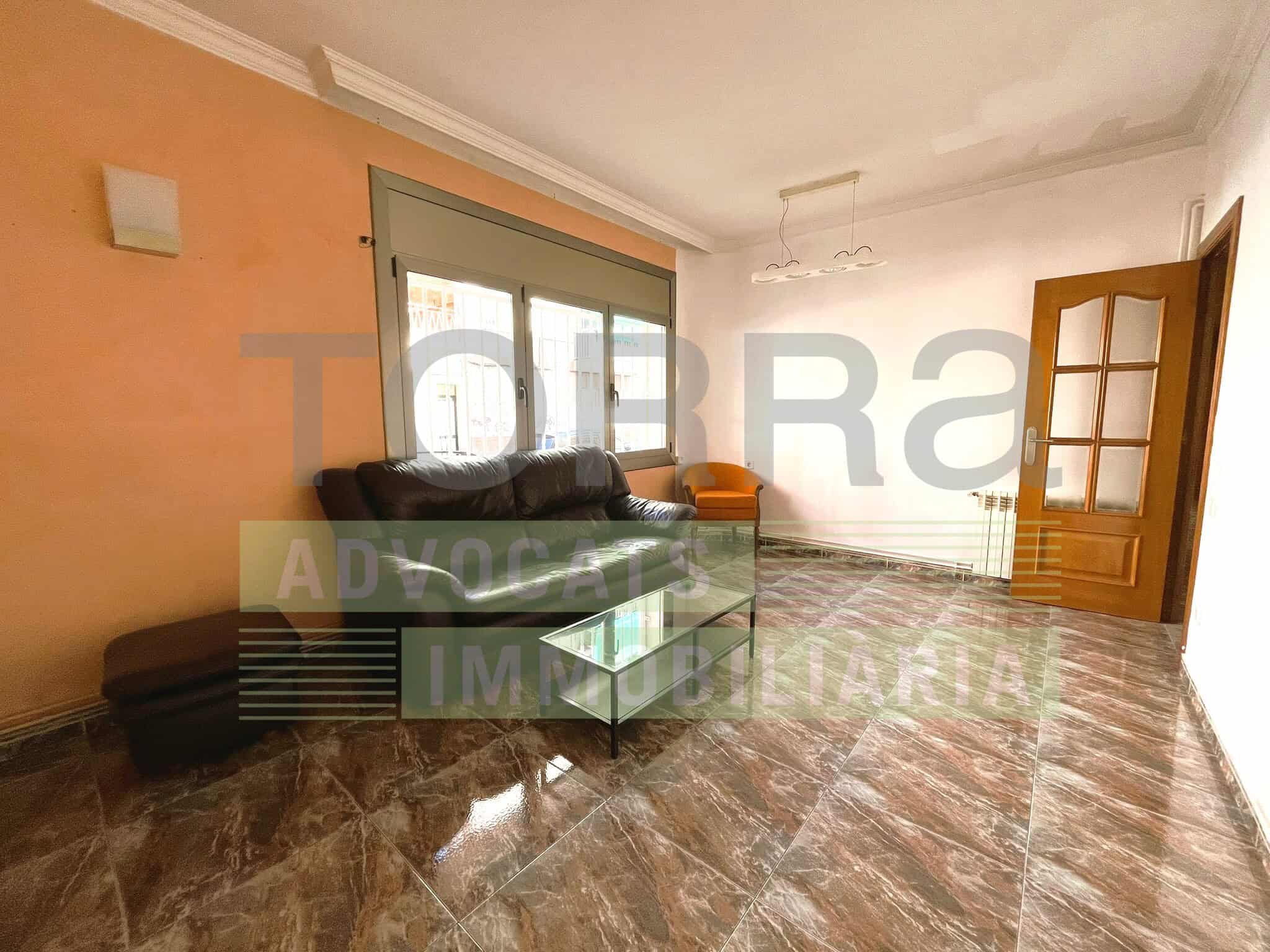 Sala de estar luminosa con sofá y mesa de centro, ideal para viviendas y alquileres inmobiliarios.