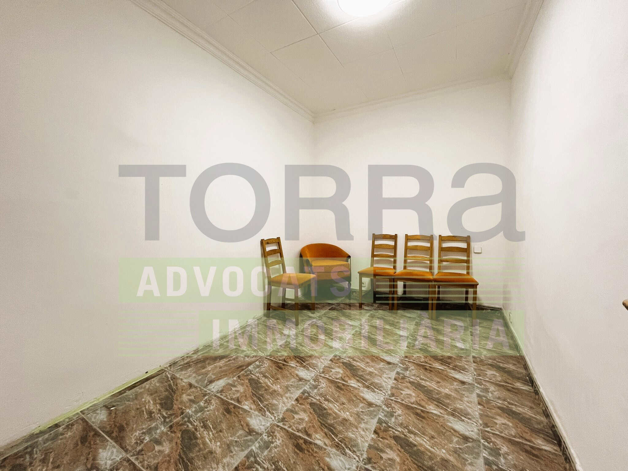 Espai d'oficina immobiliària amb mobiliari de cadires i bancs, ideal per a consultes legals i immobiliàries, amb parets blanques i sòl de rajola.