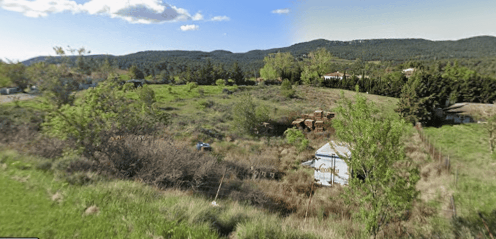 Imatge d'un terreny urbanitzable a Querol, amb vegetació i paisatge de muntanya al fons, ideal per a projectes de construcció.