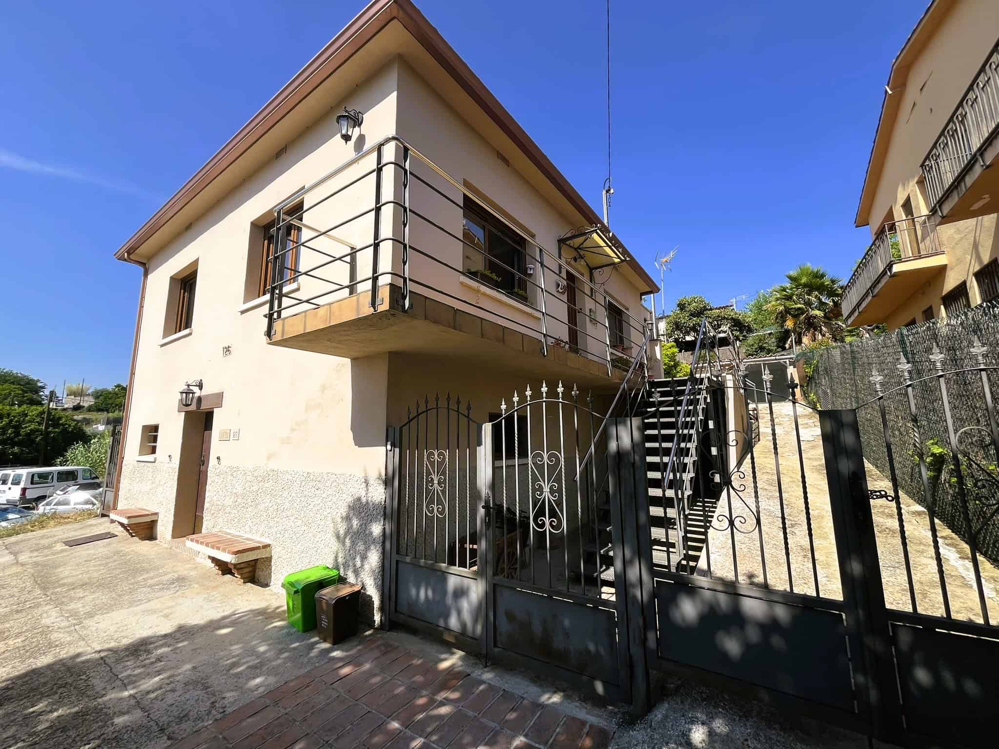 Casa independent a la zona del Castell de Palau-Solità i Plegamans amb balcó i escales exteriors, en un dia assolellat.